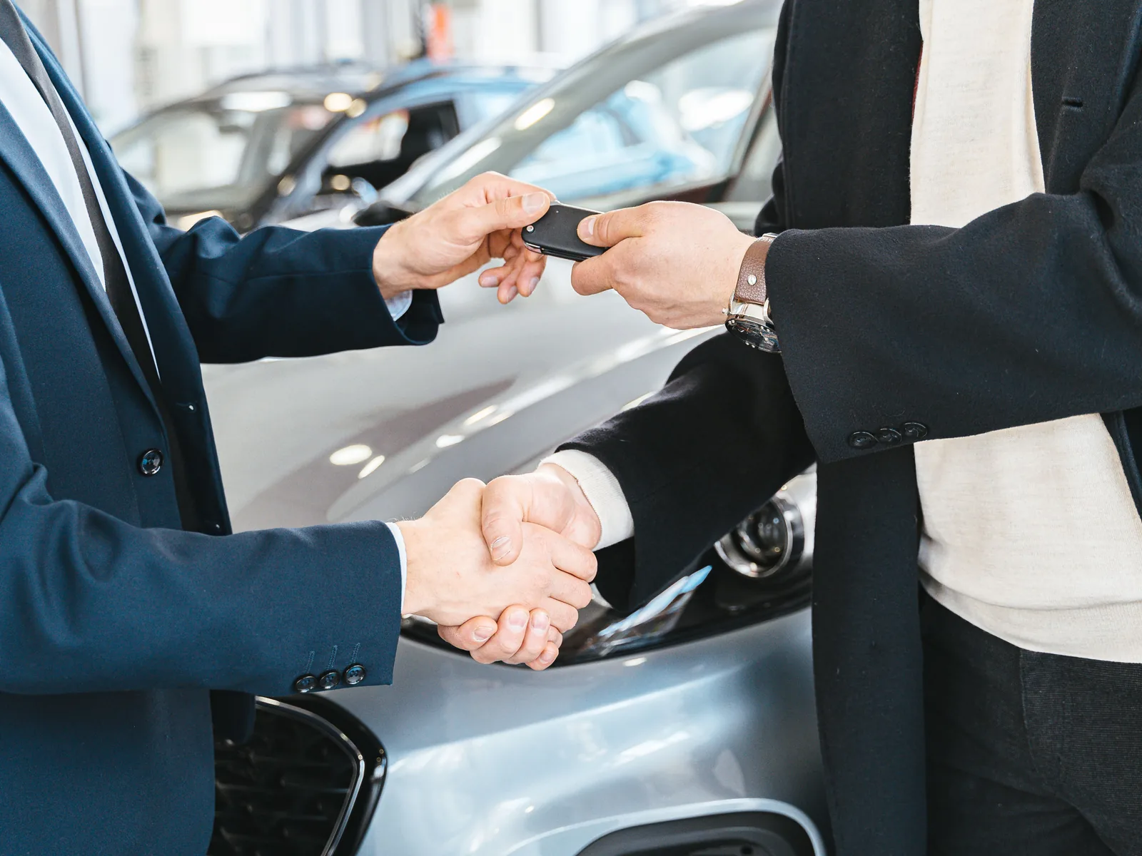Asesor entregando las llaves de un automóvil a un cliente con un apretón de manos